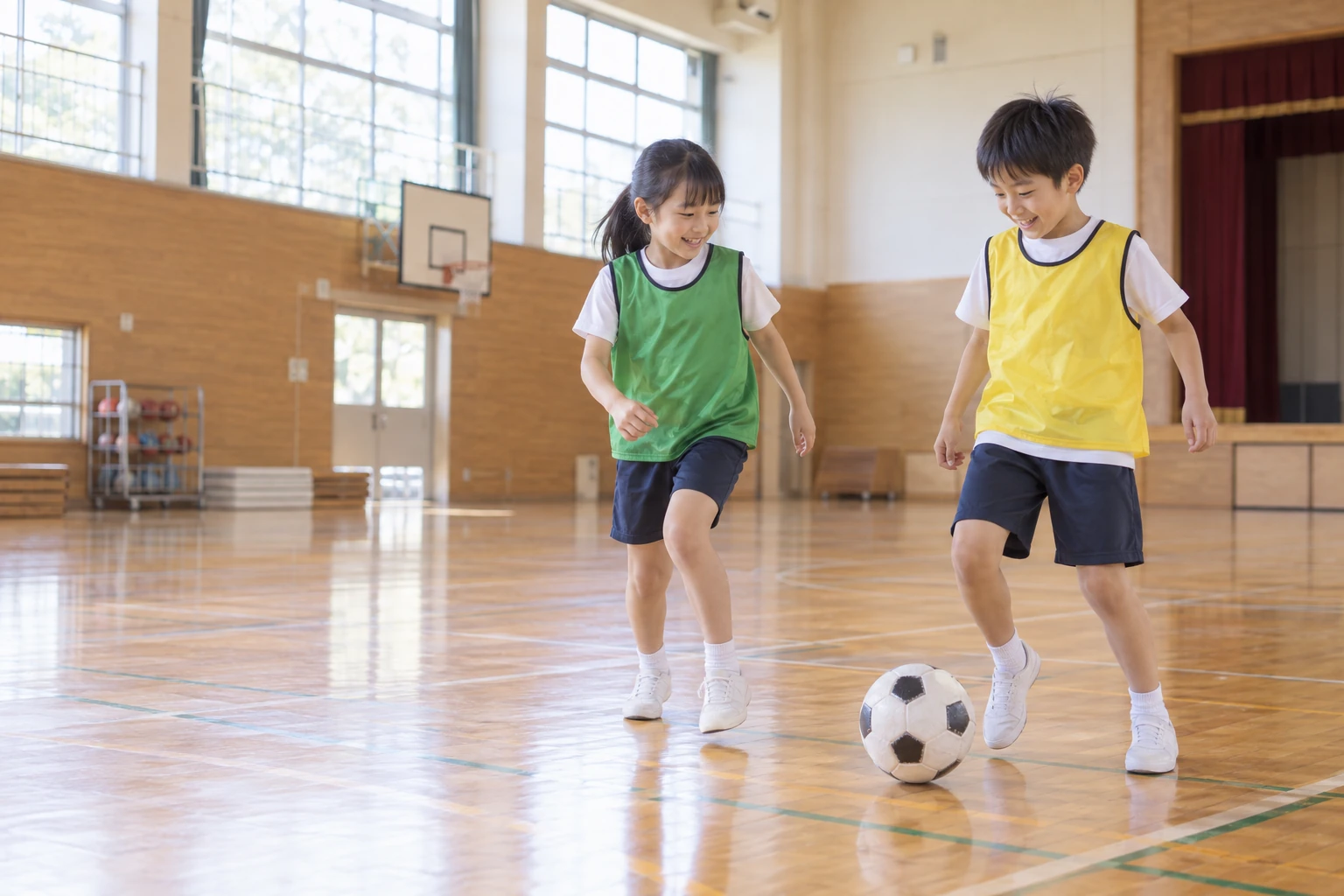 体育館でボールを追いかける男の子と女の子のイメージ
